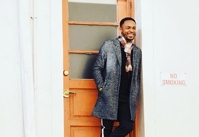 Antonio Edwards in a winter coat leaning in a wooden doorway