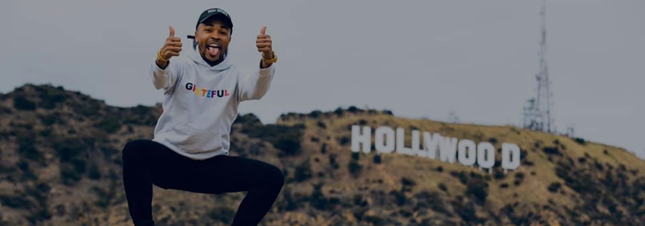 Antonio Edwards giving two thumbs up in front of the Hollywood sign